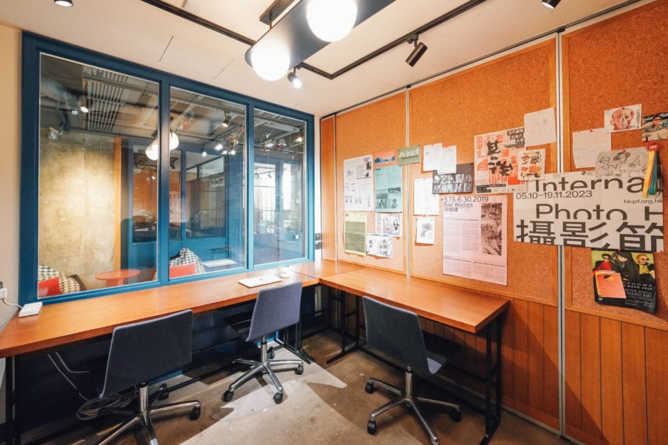Bright coworking space with modern seating, large corkboard, and ample natural light.
