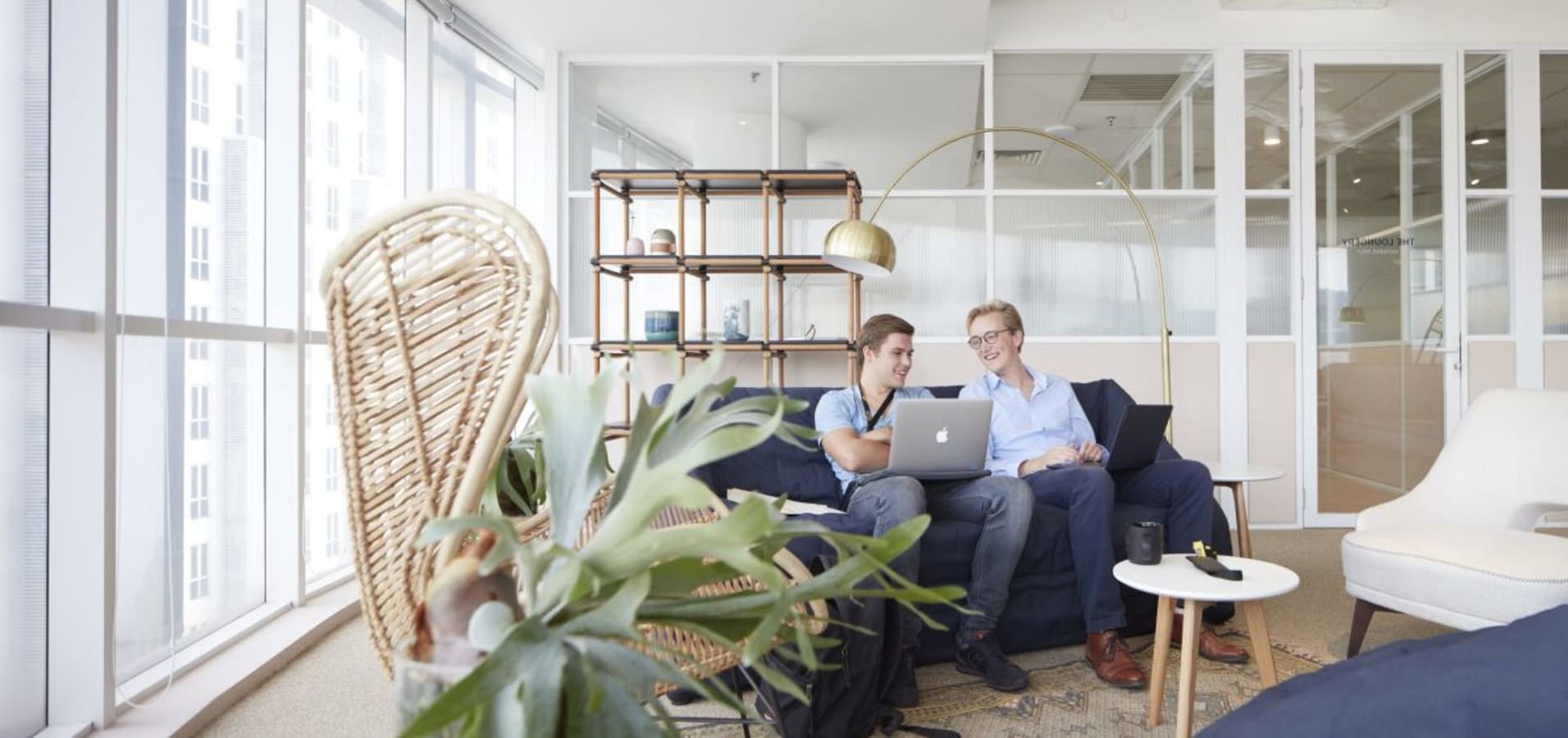 Bright coworking lounge with comfortable seating, natural light, and modern decor.