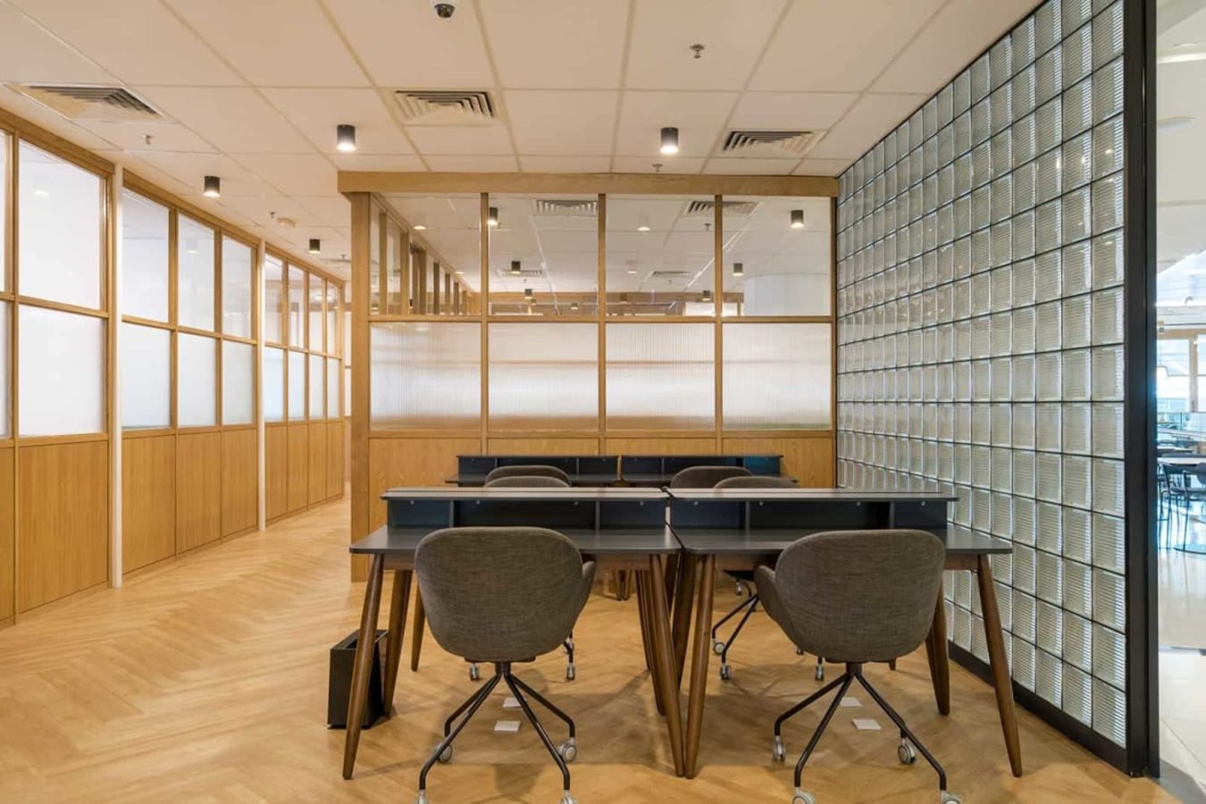 Bright coworking space with modern furniture, ample seating, and sleek glass dividers.