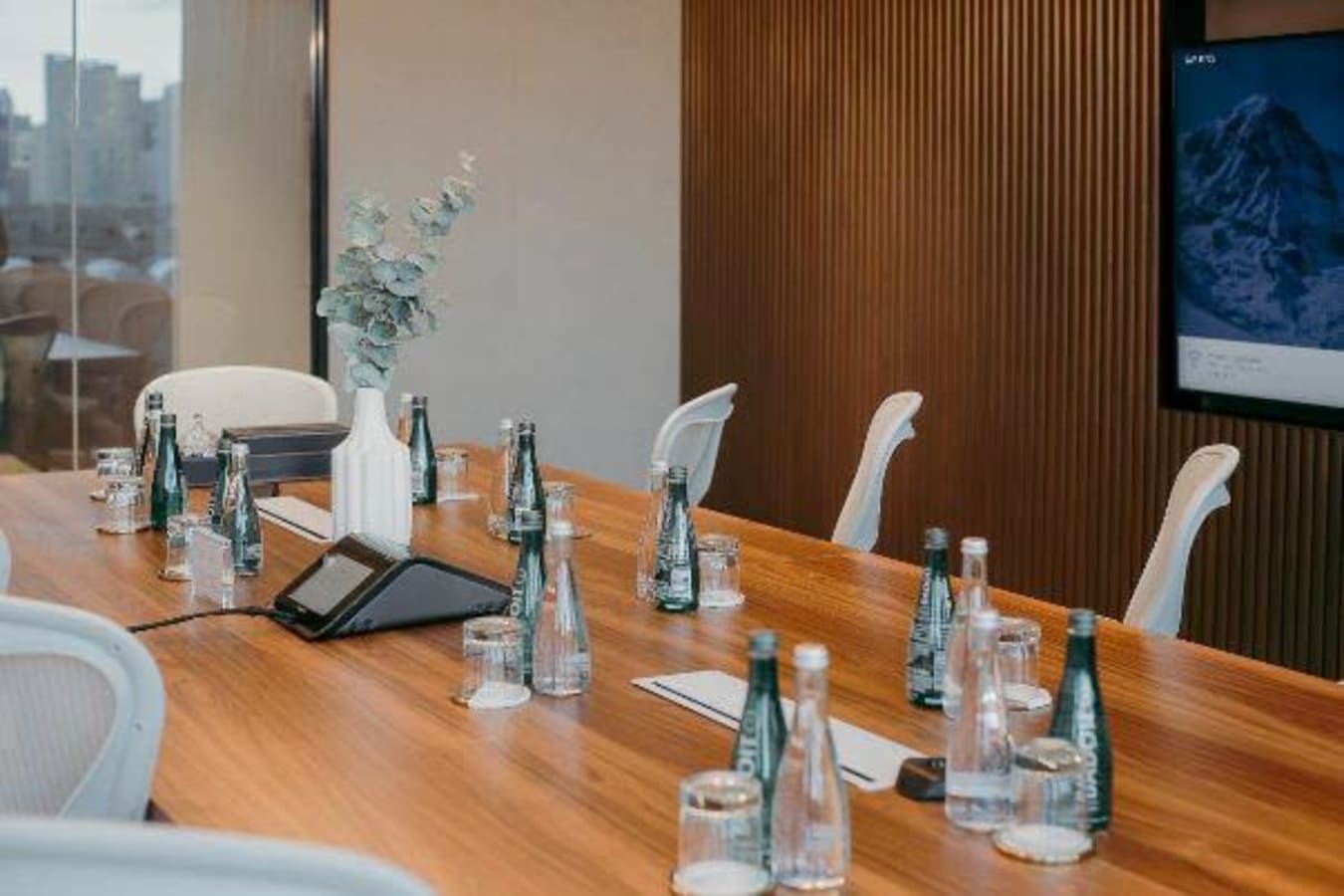 Modern meeting room with sleek wooden table, ergonomic chairs, and built-in screen in Makati City.