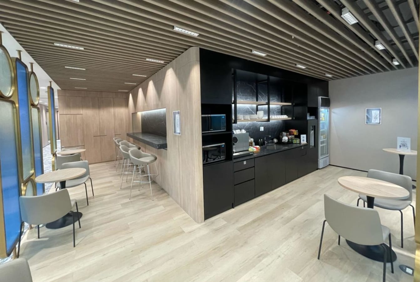 Stylish coworking kitchen area with modern seating, natural light, and ample amenities. Ideal for breaks.