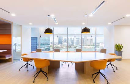 Modern coworking space with a large conference table, city views, and stylish lighting.