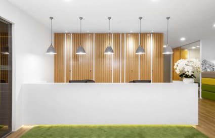 Modern coworking reception with sleek design in Raffles Place, featuring wood accents and ambient lighting.