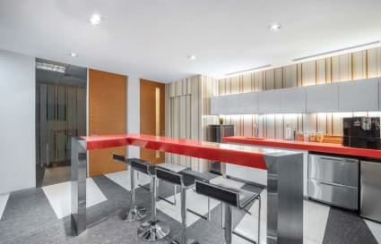 Modern coworking space with sleek bar seating, stainless steel appliances, and vibrant decor.