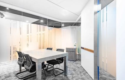 Modern meeting room with sleek table, ergonomic chairs, and frosted glass panels in a flexible workspace.