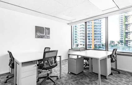 Bright coworking space with modern desks, ergonomic chairs, and a view of vibrant cityscape.