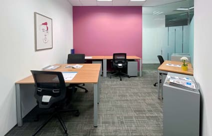 Bright coworking space with modern desks, ergonomic chairs, and vibrant accent wall.