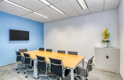 Modern meeting room with sleek chairs, vibrant accent wall, and mounted screen for presentations.