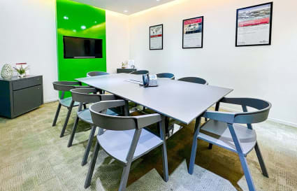 Modern conference room with sleek table, ergonomic chairs, and vibrant green accent wall.