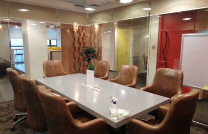 Modern coworking space with a spacious meeting room, leather chairs, and vibrant accents.