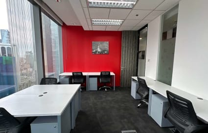 Modern office with bright red accent wall, sleek desks, and ergonomic chairs.