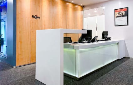 Modern reception area with sleek desk, backlit features, and warm wood accents. Ideal for client meetings.