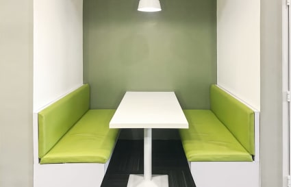 Modern booth seating with bright green cushions and a sleek white table. Cozy and inviting.