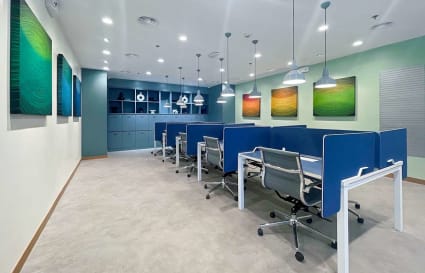Modern coworking space with sleek workstations, vibrant art, and ample lighting.