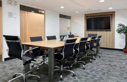 Modern conference room with ergonomic chairs, sleek table, and large screen for presentations.