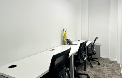 Bright, minimalistic workspace with ergonomic chairs and clean white desks in a quiet setting.