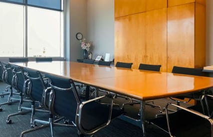 Spacious conference room with large wooden table, ergonomic chairs, and ample natural light.