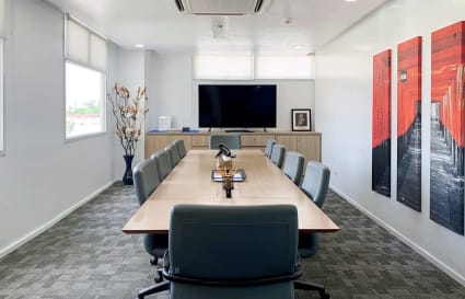 Modern conference room with seating for ten, large screen, and contemporary art accents.