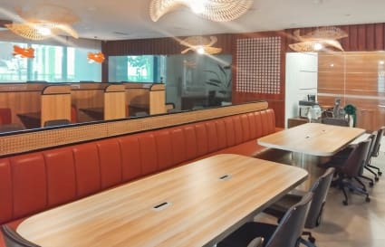 Modern coworking area with sleek booths, shared tables, and stylish pendant lighting.