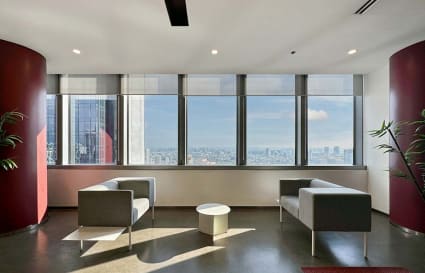 Modern office lounge with panoramic city views, sleek seating, and abundant natural light.
