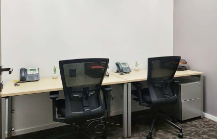 Modern workspace with ergonomic chairs, dual desks, and organized essentials for productivity.