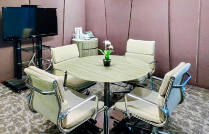 Modern meeting room with sleek chairs, round table, and a large screen for presentations.