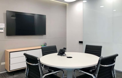 Sleek meeting room with modern amenities, featuring a round table, leather chairs, and a flat screen.