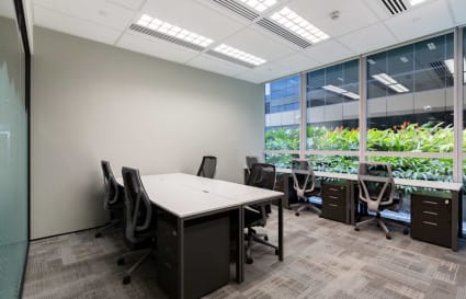 Bright coworking space with modern chairs, large windows, and greenery views in Paya Lebar.
