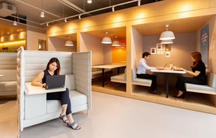 Flexible coworking space with modern booths, ample lighting, and a collaborative atmosphere.