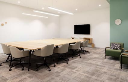 Modern coworking space with ample seating, sleek lighting, and a conference-ready setup.