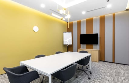 Modern meeting room with sleek furniture, vibrant wall accents, and advanced AV setup.