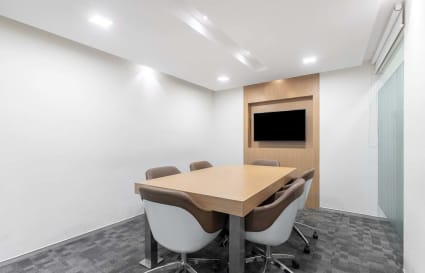 Modern meeting room with sleek chairs, minimalist décor, and a wall-mounted screen.
