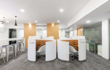 Modern coworking area with private pods, ample lighting, and sleek high-top seating. Ideal for focused work.