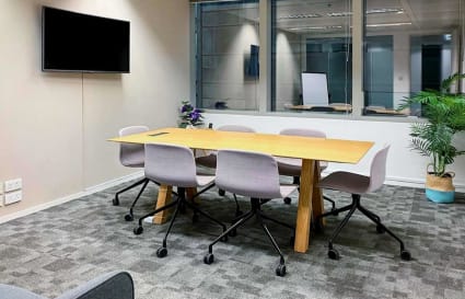 Meeting room with modern furnishings, natural light, and equipped with a wall-mounted screen. Perfect for collaboration.