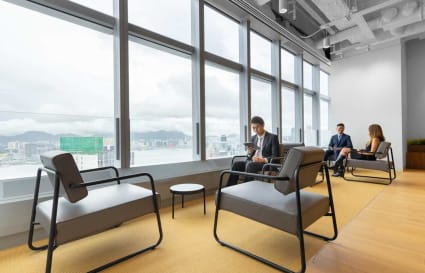 Modern coworking area with city views, featuring comfortable seating and abundant natural light.