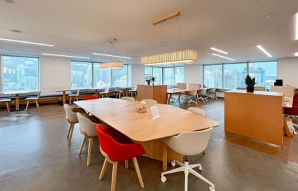 Modern coworking space featuring natural light, collaborative desks, and city views.