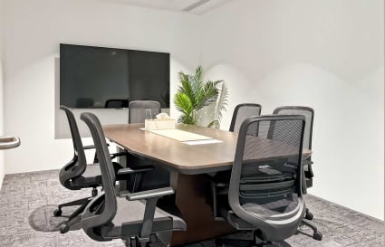 Modern meeting room with ergonomic chairs, large screen, and natural lighting. Ideal for collaboration.