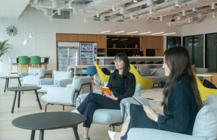 Modern coworking space with cozy seating, natural light, and a communal kitchen area.