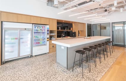 Modern coworking space with sleek kitchen, ample seating, and vibrant vending amenities.