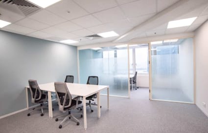 Modern coworking space with stylish chairs, modular tables, and a private meeting room on Wai Yip Street.