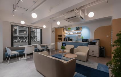 Modern coworking space in 德輔道中 with stylish seating, natural light, and a well-equipped kitchenette.