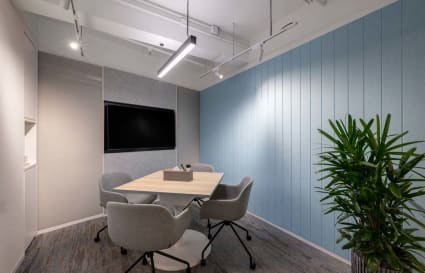 Modern meeting room with stylish chairs, a large screen, and vibrant decor in 中環 coworking space.