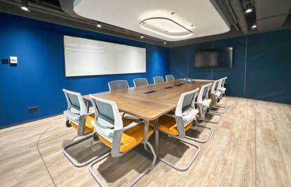 Sleek meeting room with modern furniture, a large conference table, and digital presentation screen.