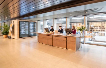 Modern coworking space with elegant reception, ample natural light, and sleek furnishings.
