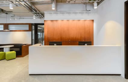 Modern coworking space with sleek reception, cozy breakout area, and inviting lighting.