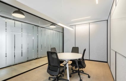 Modern meeting room with sleek furniture, frosted glass walls, and ample lighting. Perfect for collaboration.