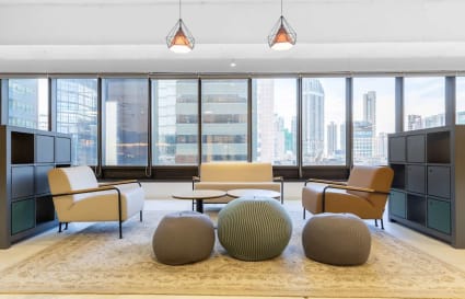 Bright coworking lounge with modern seating and city views, perfect for collaboration.