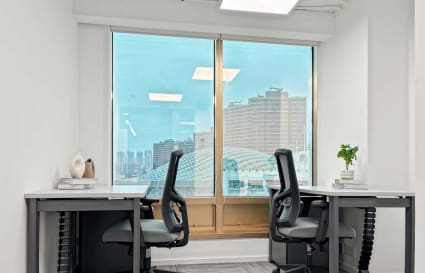 Bright coworking space with ergonomic chairs, sleek desks, and a stunning city view.