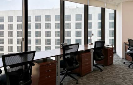 Bright workspace with modern desks, ergonomic chairs, and floor-to-ceiling windows.