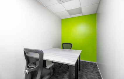 Compact coworking space with vibrant green accent wall and modern seating. Ideal for focused work.